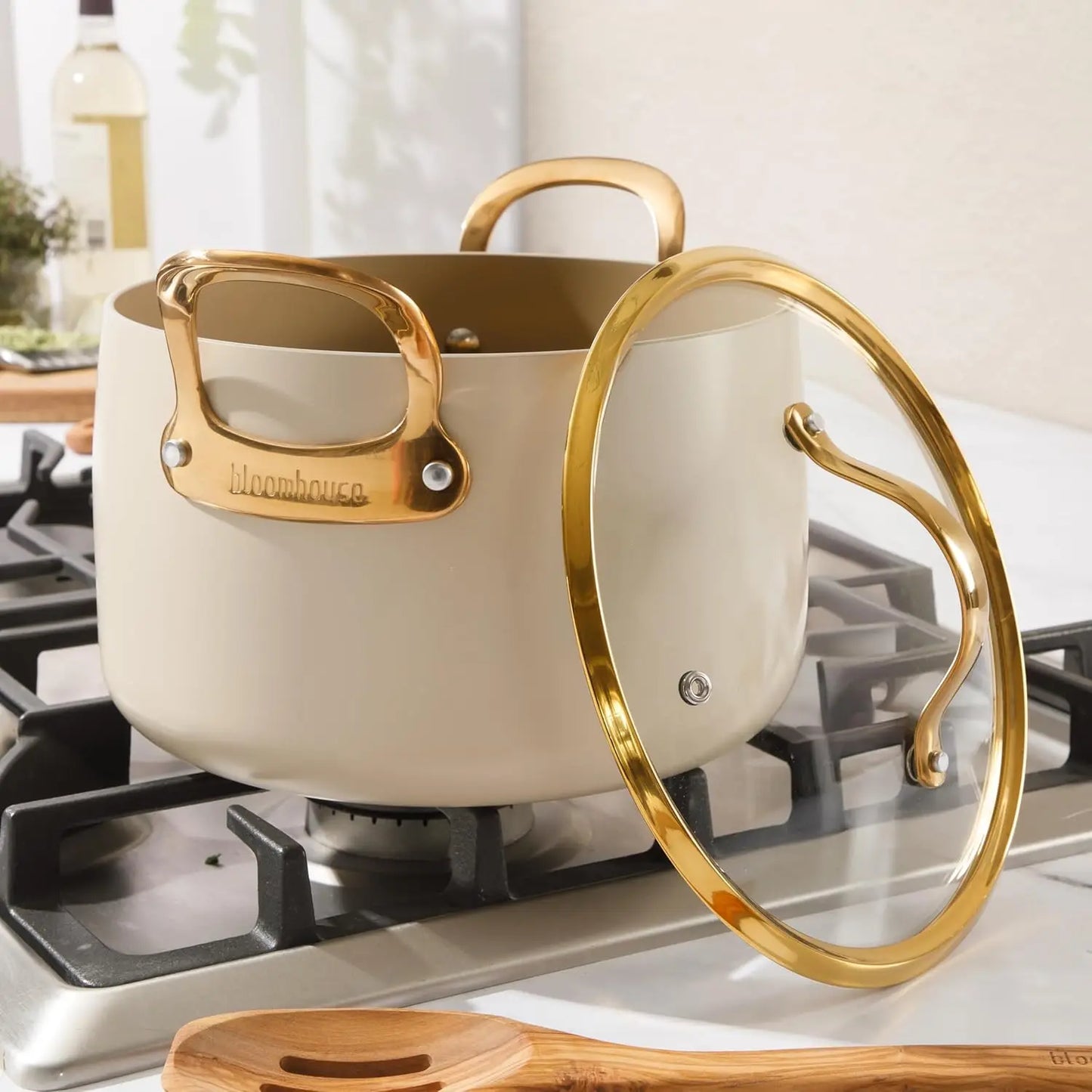 Cream-colored pot with gold handles on a stove, featuring the Bloomhouse brand.